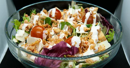 Ensalada fresca y deliciosa con pollo a la parrilla, aderezada con salsa César casera.